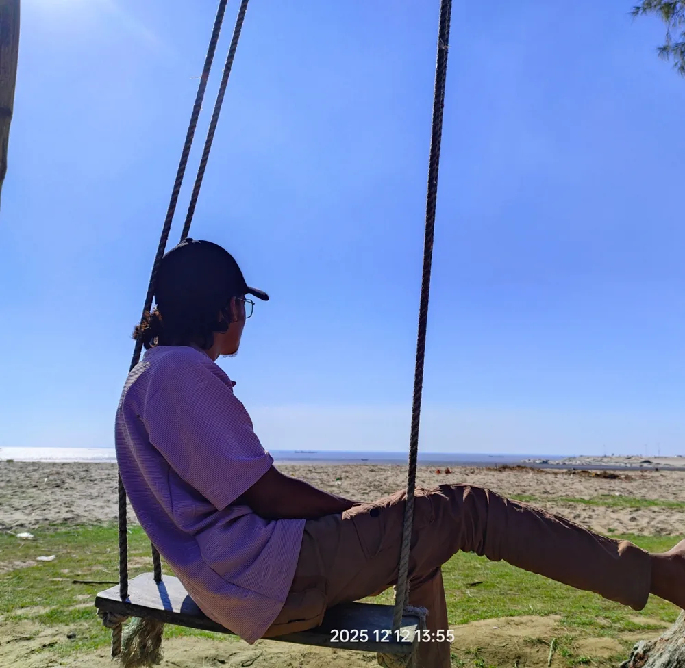 Saiem sitting on a swing overlooking the shore